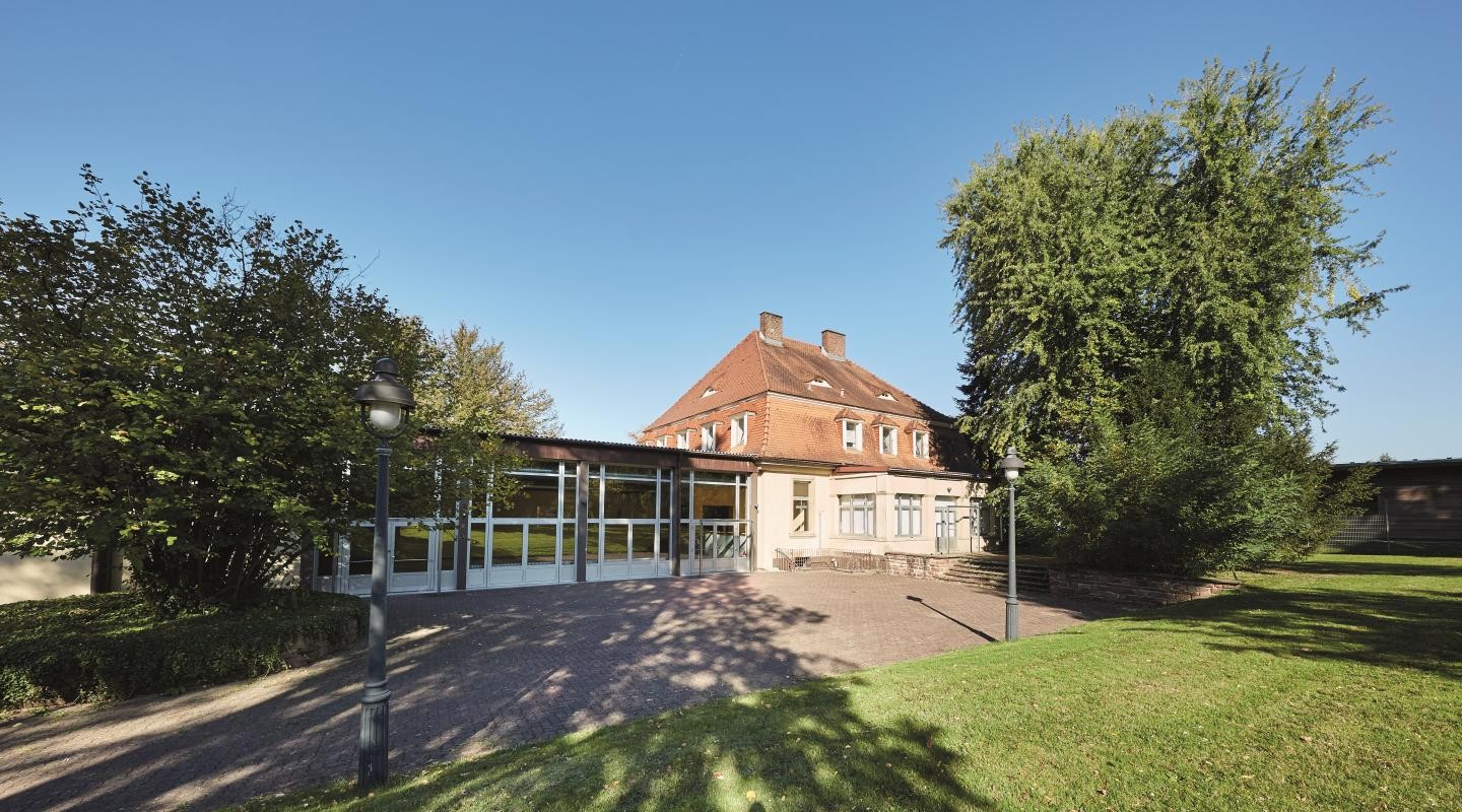 Kasino Außenbereich Kasino Ansicht des Außenbereiches mit grüner Wiese und grünen Bäumen bei Sonnenschein