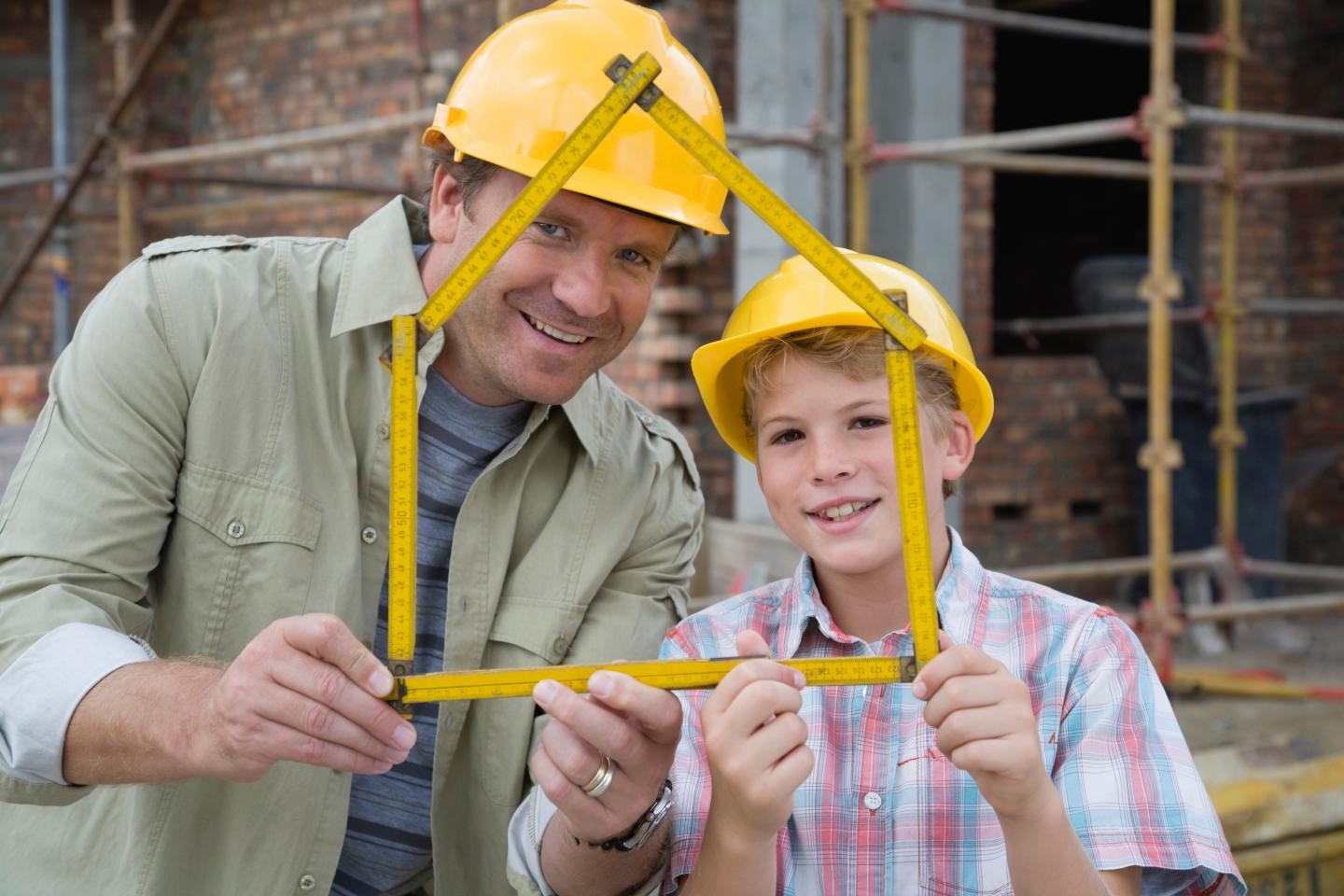Bild einer Baustelle mit Vater und Sohn mit Bauhelmen im Vordergrund