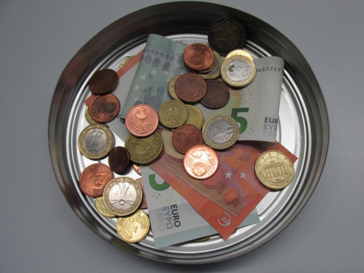 Geöffnete Blechdose mit Münzgeld und Geldscheinen