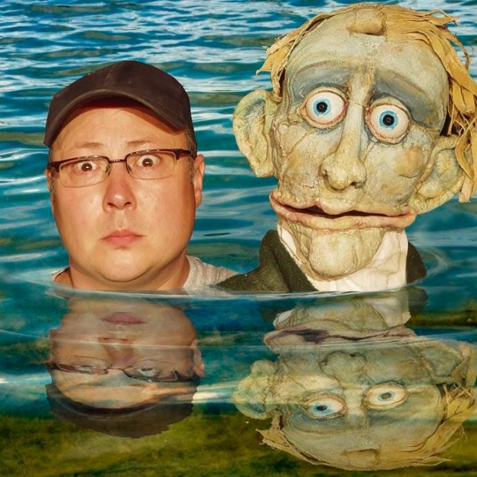 Der Puppenspieler Carsten Dittrich mit der Puppe Hugo Hagedorn in einem See.