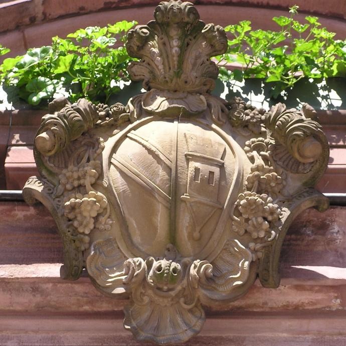 Steinernes Wappen über dem Rathausportal im sommerlichen Flor