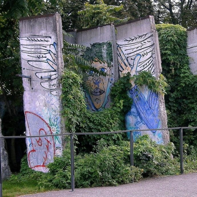 Man sieht fünf ehemalige Teile der Berliner Mauer mit Graffitis