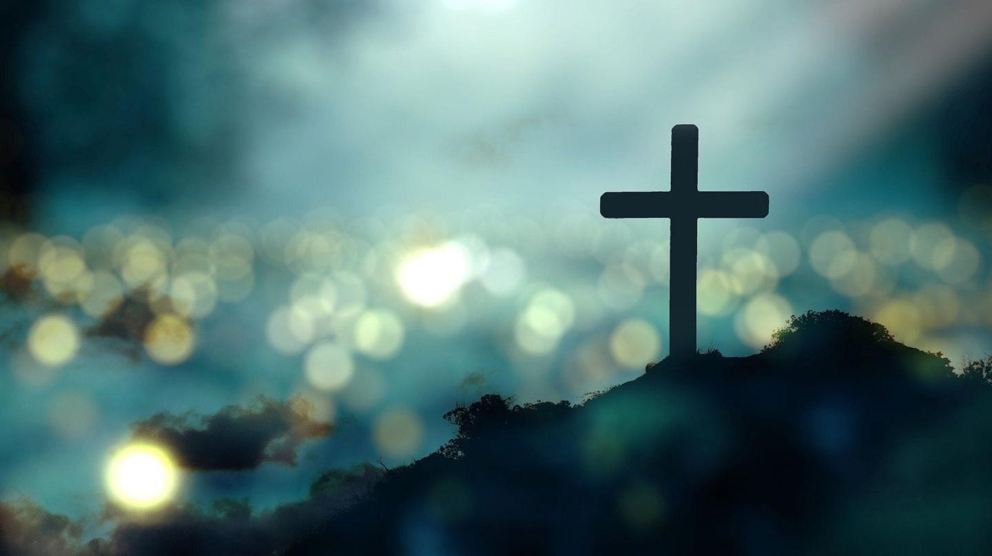 Ein dunkles Kreuz vor hellerem, flirrendem Hintergrund.