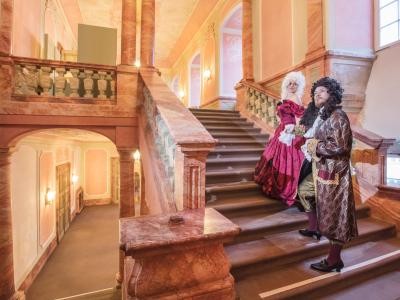 Zwei Personen in Barockkleidern im Treppenhaus des Schlosses