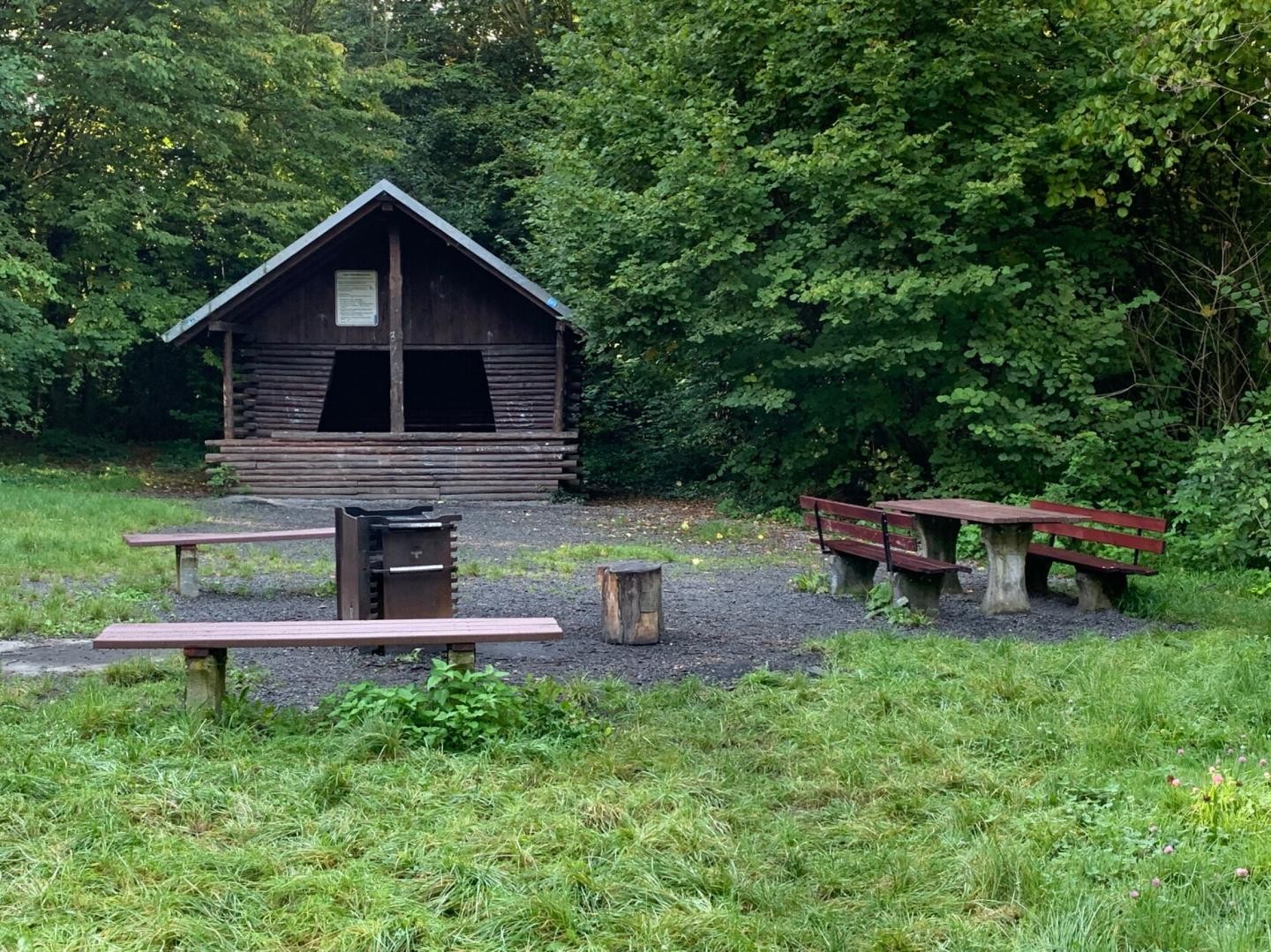 Eine Holzhütte mit mehreren Sitzbanken und Tischen