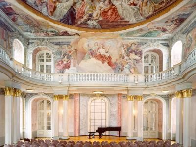 Bestuhlter Asamsaal mit Flügel, im Hintergrund prunkvolles Deckengemälde