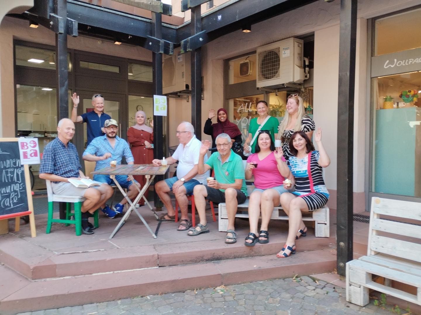 Gruppe Menschen vor dem Eingang des Begegnungsladens, teilweise mit Eiskaffee in der Hand