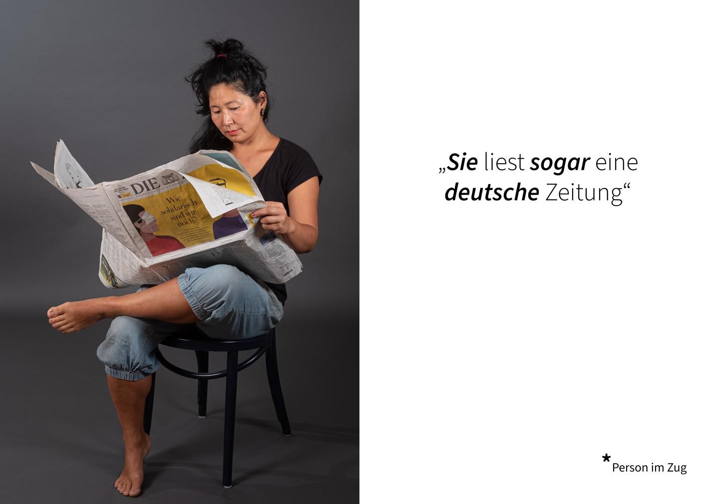 Eine Frau sitzt auf einem Stuhl und liest Zeitung