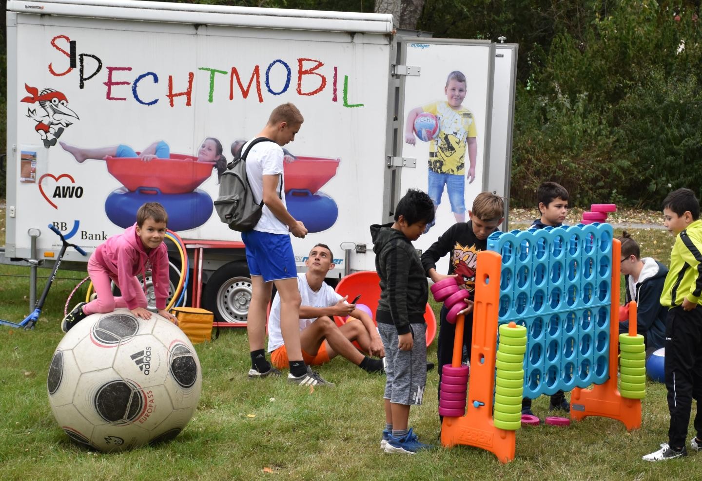 Spechtmobil mit spielenden Kindern im Vordergrund