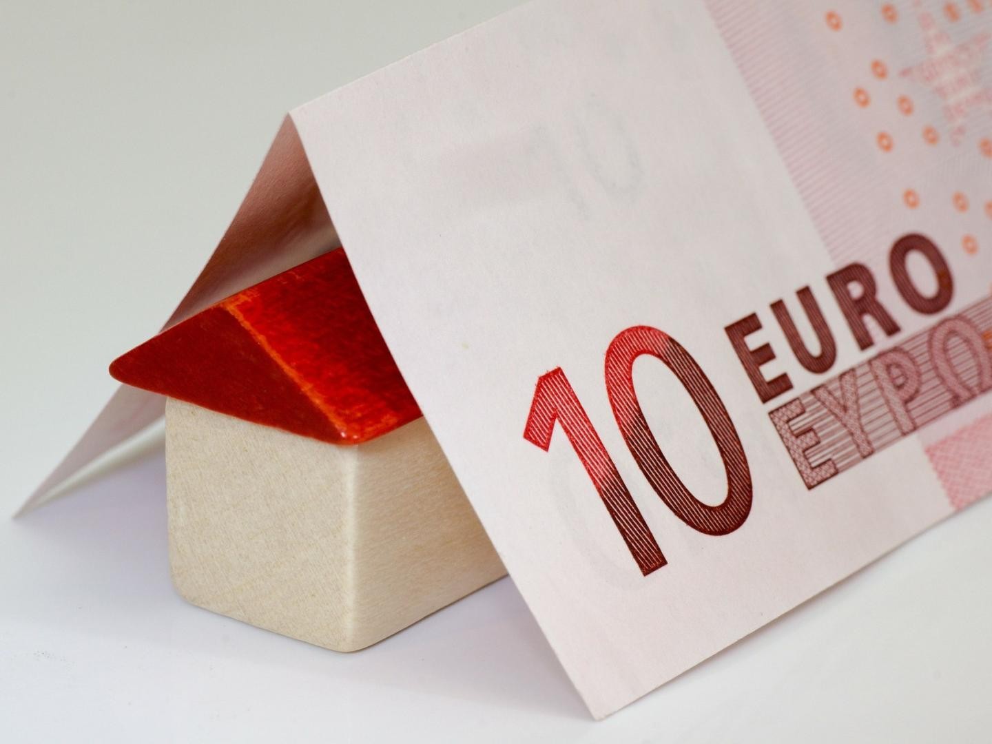 Haus aus Bauklötzen mit einem Dach gefaltet aus einem Geldschein