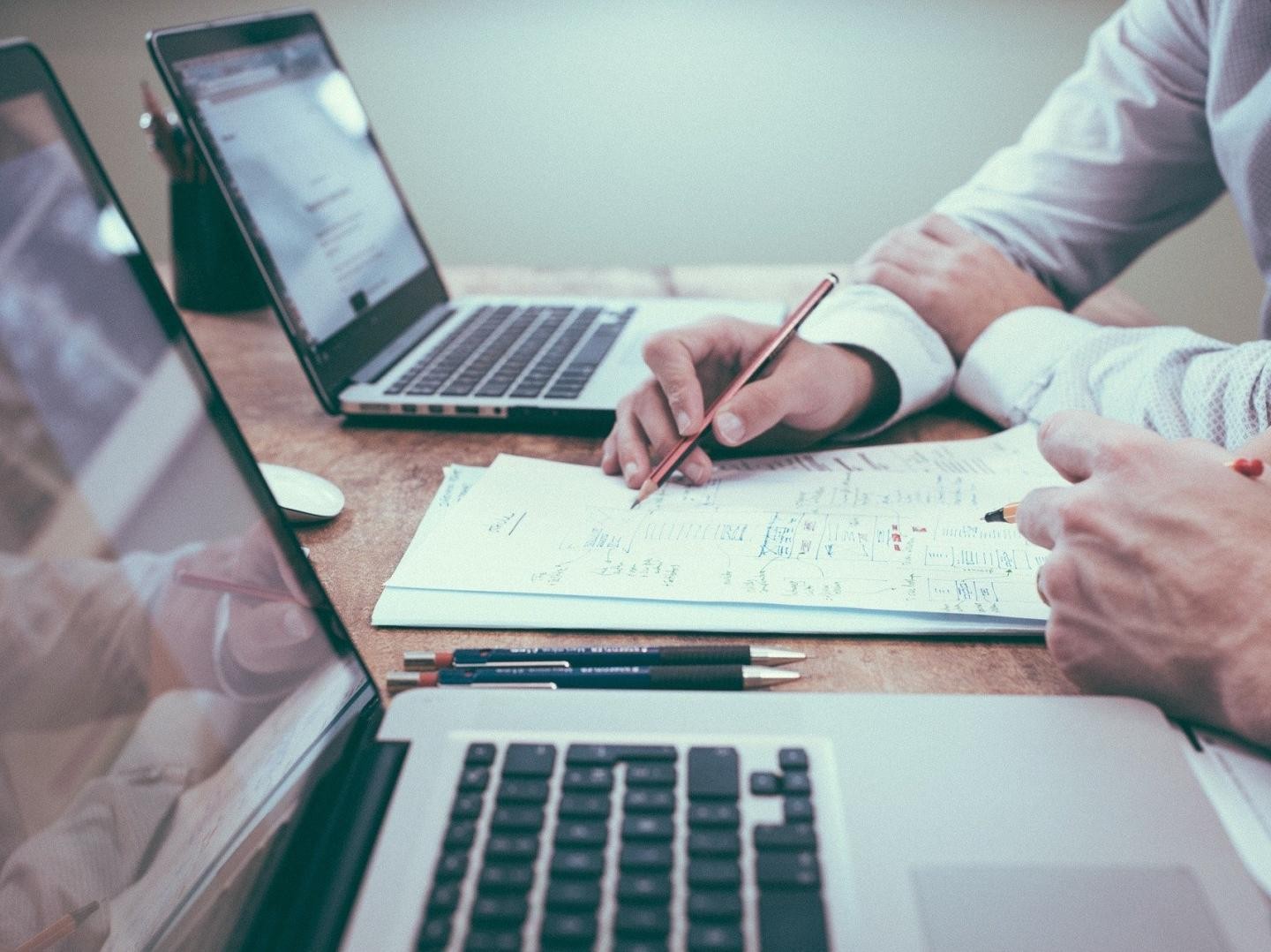 Menschen am Schreibtisch beim Arbeiten an Laptops