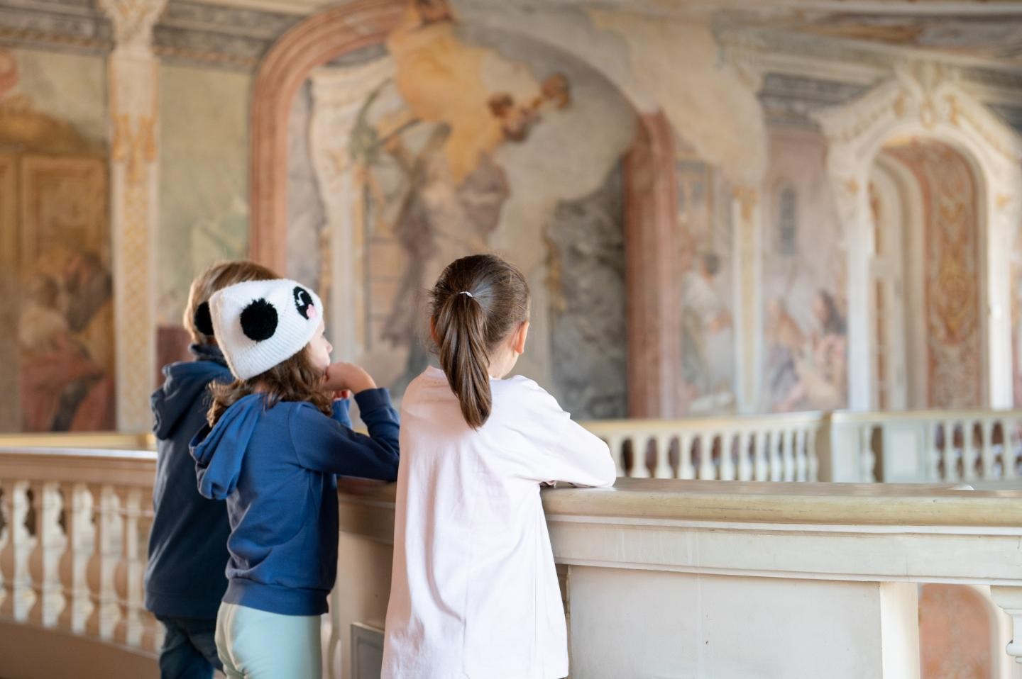 Acht Kinder sitzen um eine Kindergeburtstagsmitarbeiterin herum, die etwas zeigt und erklärt