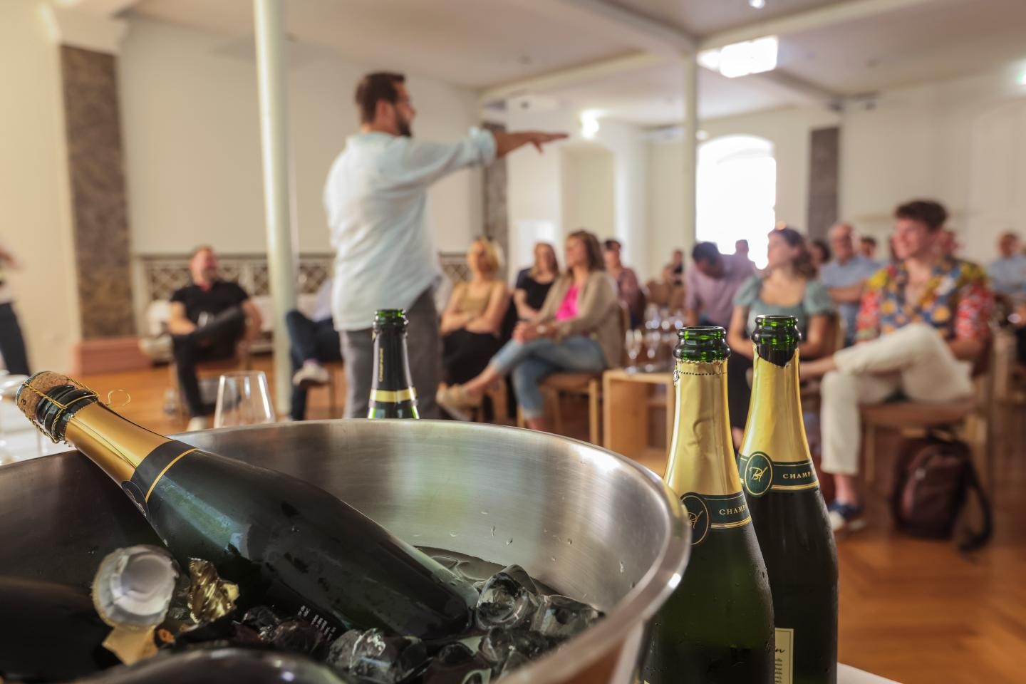 Bild mit Champagnerflaschen und im Hintergrund mehrere Personen