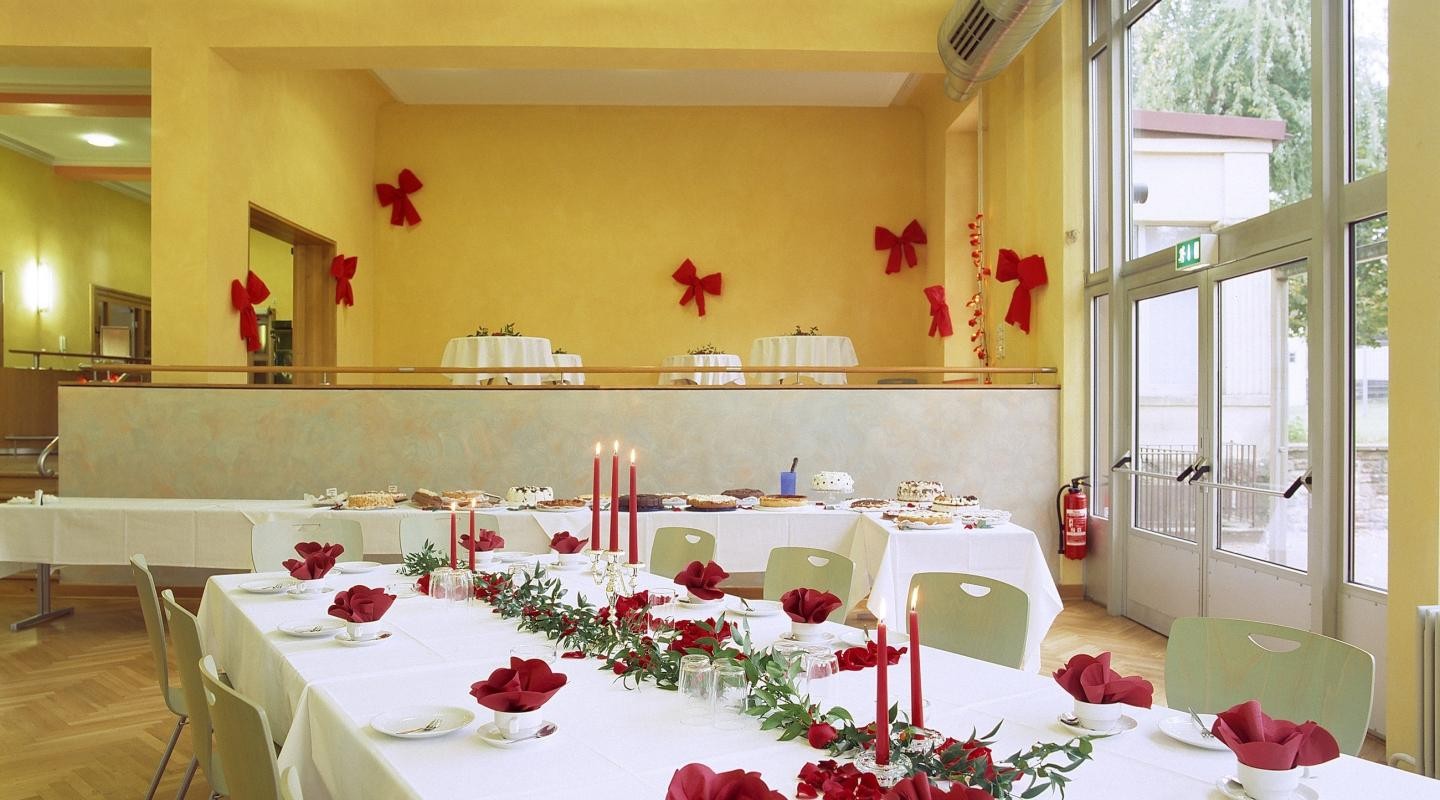Kasino von innen mit Langtischen für Bankett, weißen Tischdecken und rotem Tischschmuck