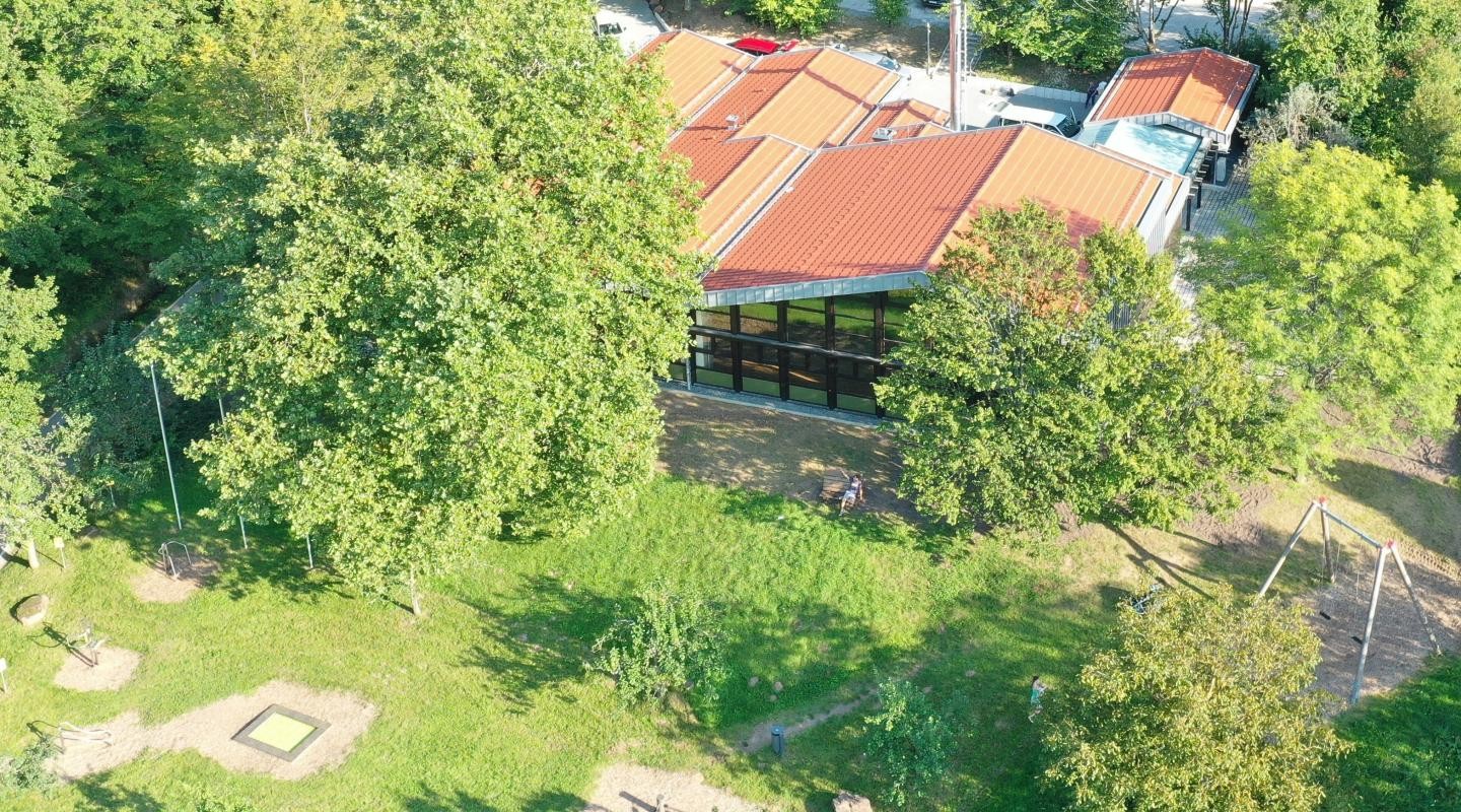 Waldsaumhalle Außenansicht von oben auf die Halle mit grünen Bäumen und Bewegungspfad