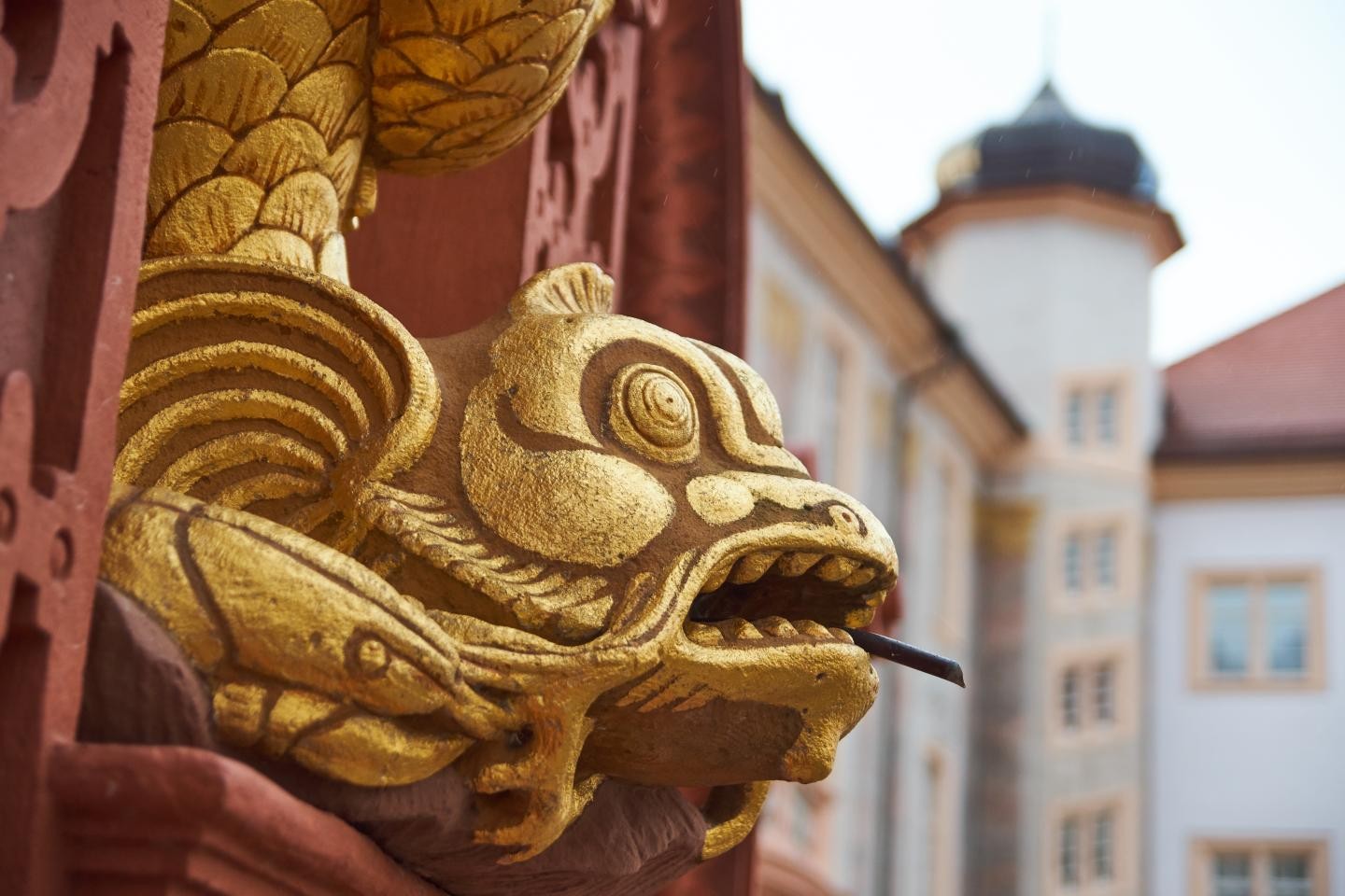 Vergoldeter Delphinkopf; im Hintergrund das Ettlinger Schloss