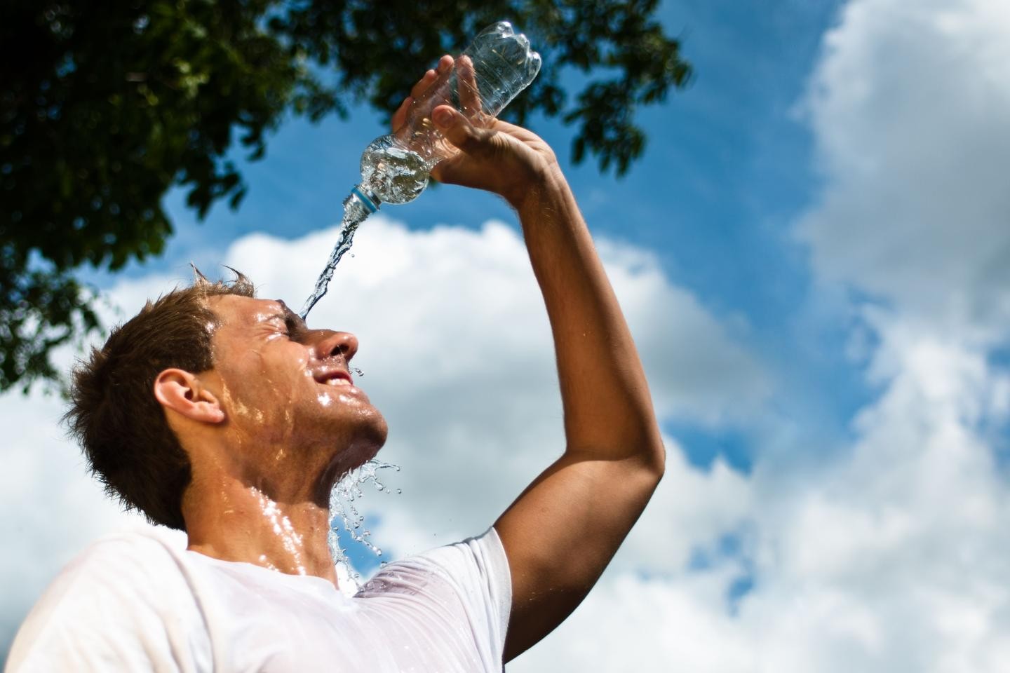 Ein Mann schüttet aus einer Flasche Wasser über sich