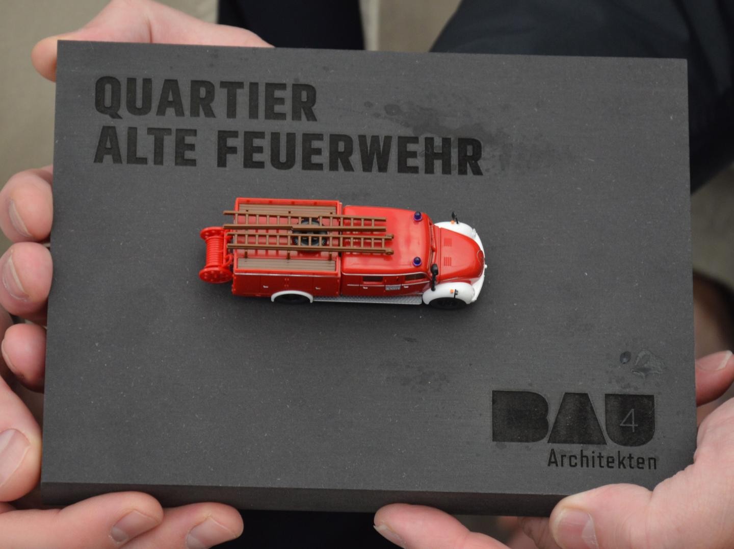 ein historisches kleines Feuerwehrauto auf einer schwarzen Platte