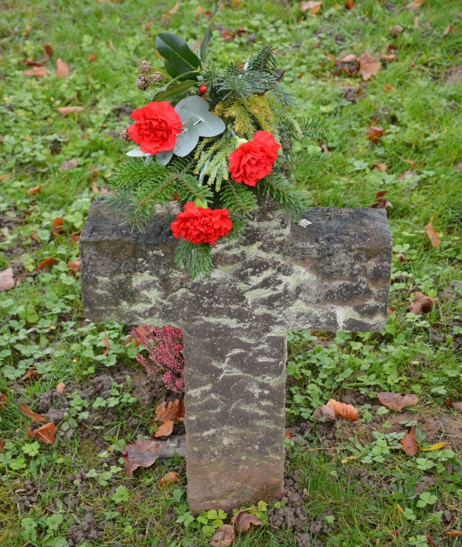 ein Sandsteinkreuz mit einem kleinen Blumengebinde