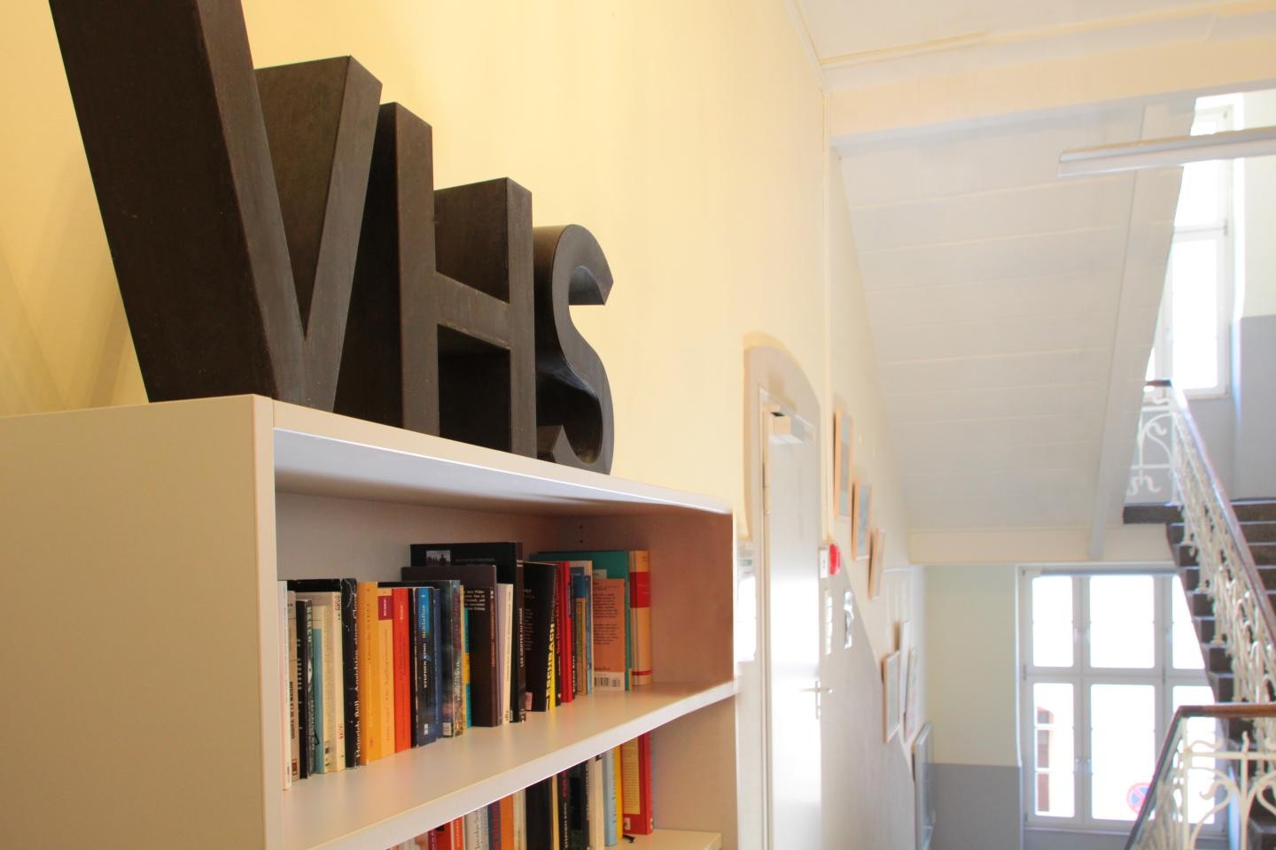 Ein Bücherregal, auf dem in großen Buchstaben ein V, ein H und ein S steht