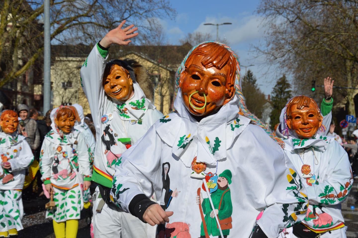 Rosenmontagsumzug; fünf Maskenträger mit Häs und Kleidle im Sonnenschein