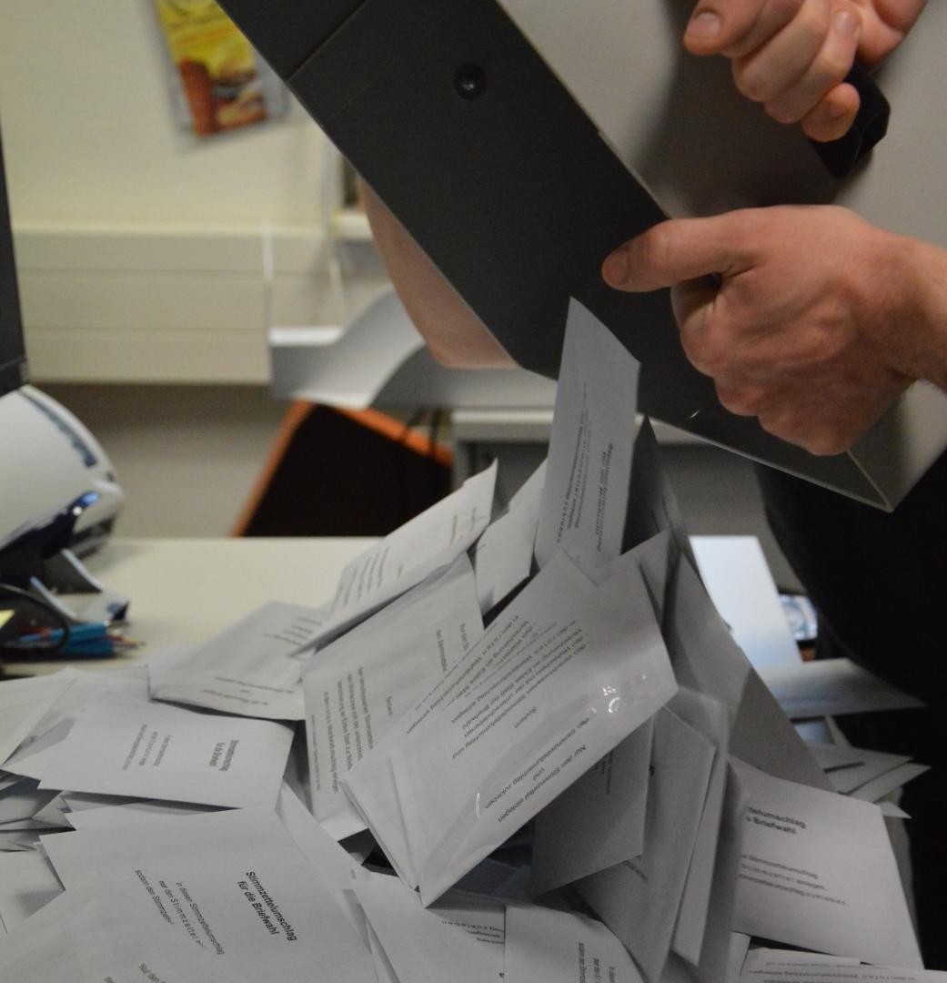 Aus der Wahlurne purzeln Wahlbriefe heraus. 