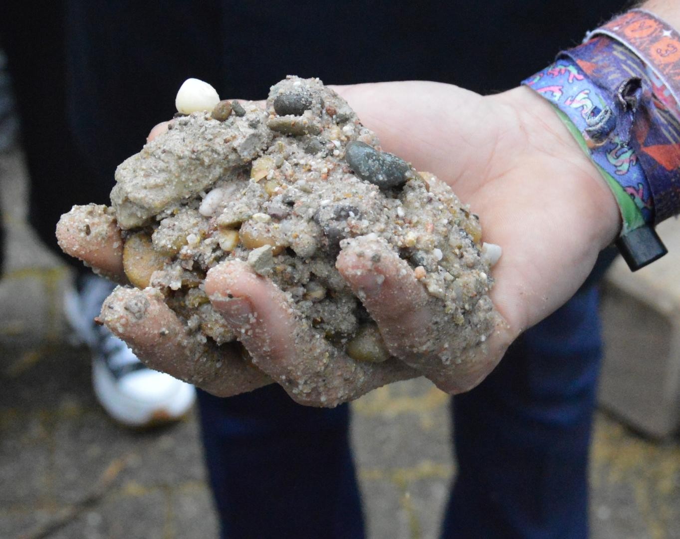 ein Hand voll mit Kiesel und fluffigen breiigen sandigen Material
