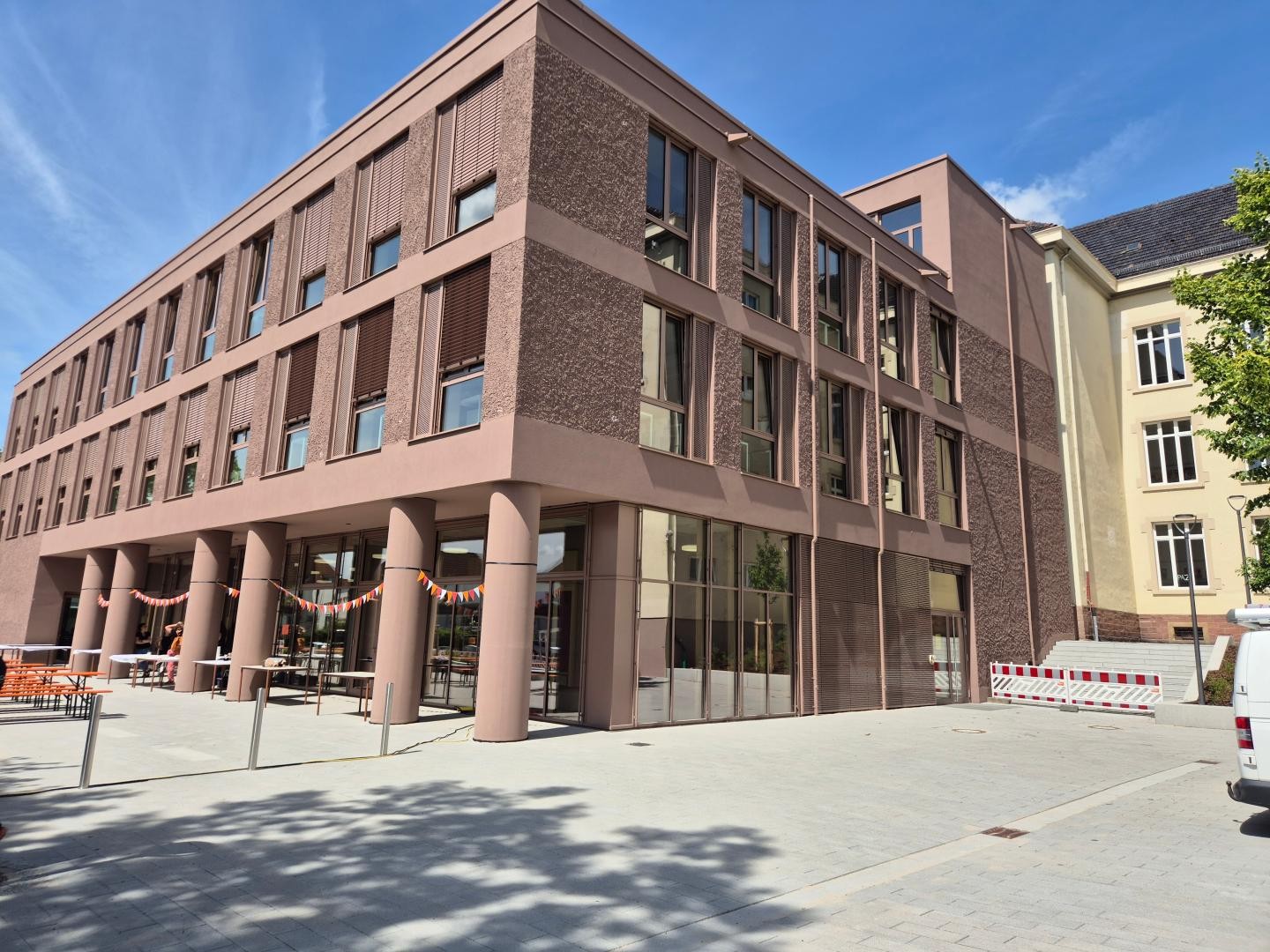 Der sandsteinfarbene Neubau, rechts der Altbau mit gelbem Putz.