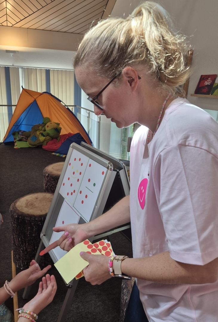 bibliotheksmitarbeiterin jessica Wegner verteilt rote Punkte an Kinder