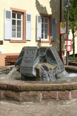 Zwölfeckiger Brunnentrog mit vier Wappentafeln auf Sockel in der Mitte des Brunnens