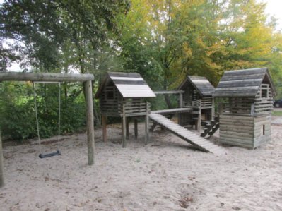 Hütten und Schaukel auf Klettergerät auf Sandspielfläche