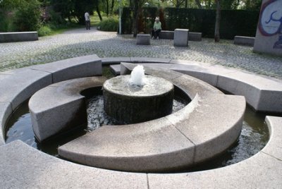 Wasserschnecke bestehend aus mehreren Steinquadern um Stein angeordnet, aus dem Wasser aufsteigt