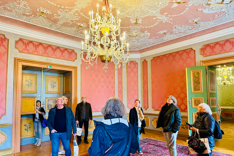 Eine Reisegruppe bei einer Schlossführung im prunkvollen Saal des Schlosses Ettlingen.