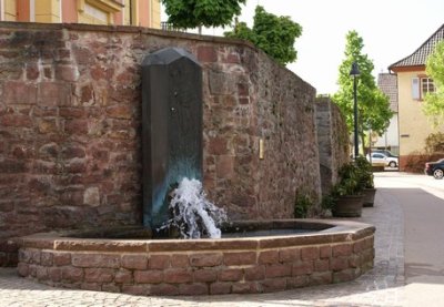 Zehneckiges Brunnenbecken mit Bronzerelief, auf dem der heilige Dionysius abgebildet ist