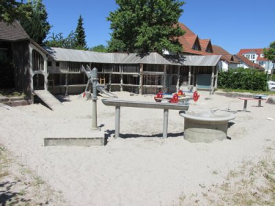 Wasserpumpe mit Rinne zu Wasserbecken auf Sandspielfläche