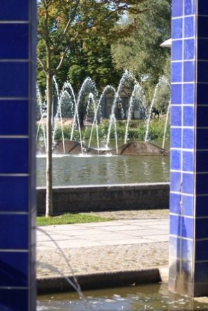 Stelen mit blauen Fliesen, aus den seitlich Wasser spritzt, in Nahaufnahme