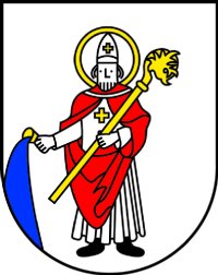 Das Wappen Schöllbronns zeigt den heiligen Bonifatius mit Umhang, Mitra und Krummstab, mit der rechten Hand aus einem Kelch Wasser gießend 
