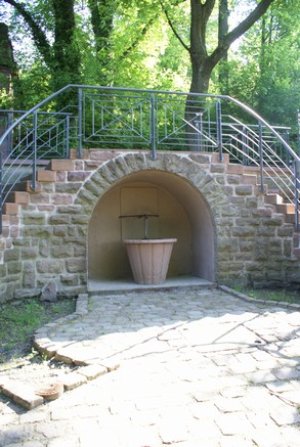 Unter Treppenaufgängen in Arkade stehender Brunnentrog
