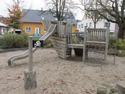 Kletterspielgerät in Form eines stilisierten Schiffes mit Rutsche auf Sandspielfläche